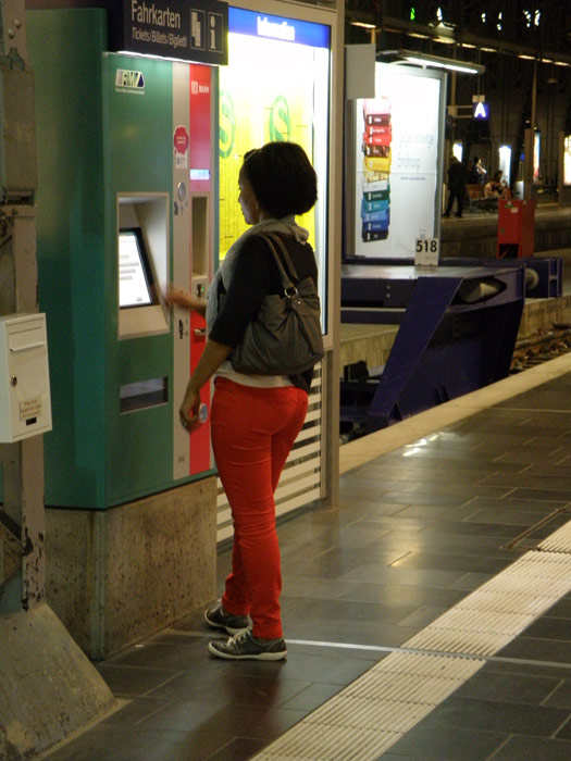 Viajera comprando su billete en una máquina autoventa en la cabecera de andén